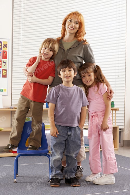 Preview: Teacher And Children (4-6) Standing In Classroom, Smiling, Portrait