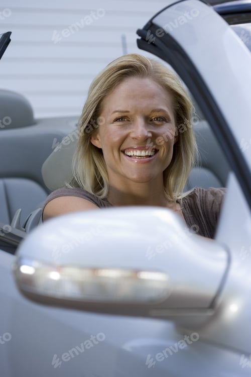 Preview: Woman Sitting In Driving Seat Of Parked Convertible Car On Driveway, Smiling, Portrait