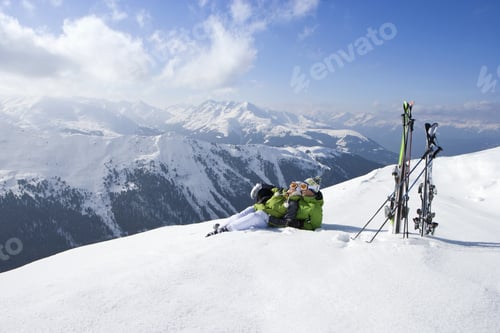 Preview: Couple Laying In Snow On Mountain Top With Skis