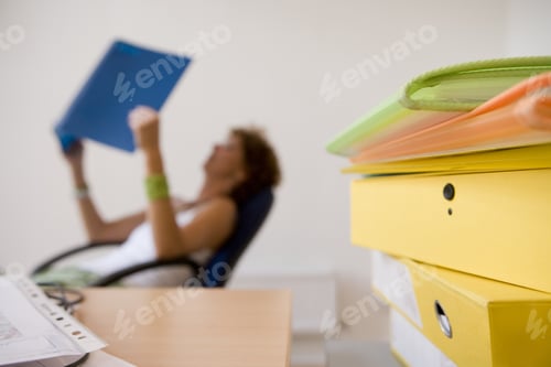 Preview: Files By Desk, Woman Reading In Background