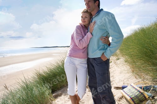 Preview: Loving Couple Hugging On Sand Dunes By Beach With Picnic Basket