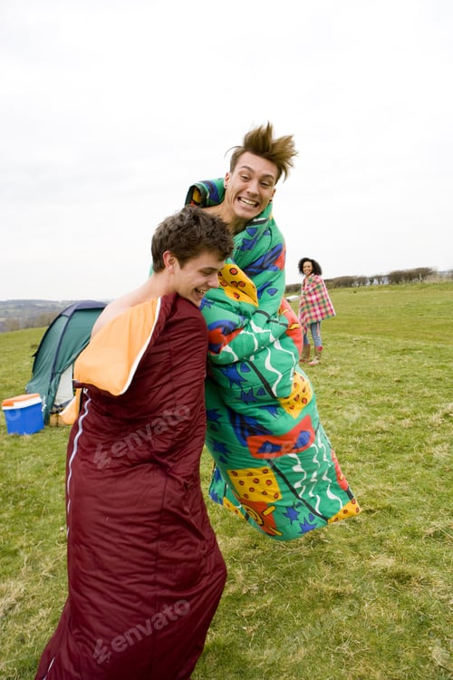 Preview: Excited Men Jumping In Sleeping Bags At Outdoor Festival