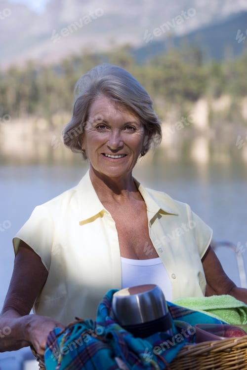 Preview: Senior Woman Carrying Picnic Hamper Beside Lake, Smiling, Portrait