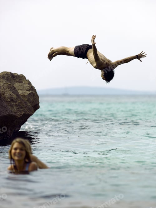 Preview: Young Woman In The Sea With A Young Man Diving Behind Her