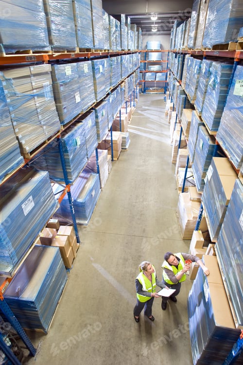 Preview: Distribution Warehouse Workers With Paperwork Checking Shelf Stock