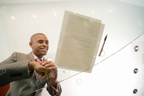 Preview: Businessman In Office Looking At Contract Through Glass Table