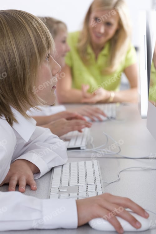 Preview: Teacher Helping Students Working On Computers In School Computer Lab