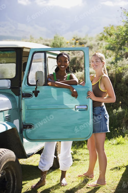 Preview: Two Young Women Standing Beside Parked Jeep, Leaning On Turquoise Door, Smiling, Portrait