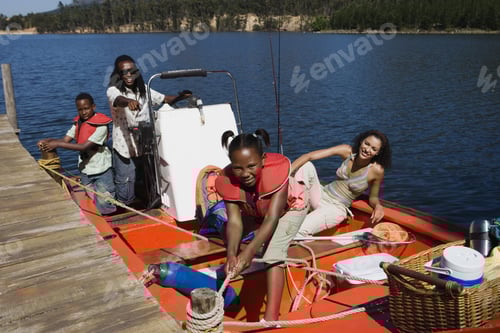 Preview: Family Standing In Motorboat Beside Lake Jetty, Girl Tying Rope To Mooring Post, Smiling, Portrait