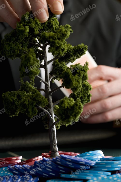 Preview: Man Placing Model Tree On Pile Of Gambling Chips On Table, Mid Section