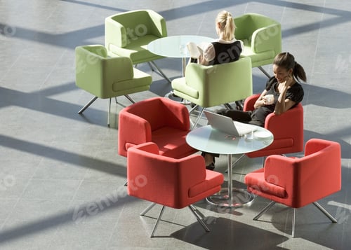 Preview: Two Businesswomen Sitting At Tables In An Office Building