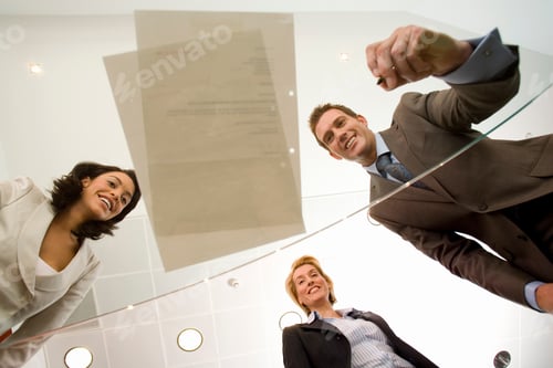 Preview: Business Colleagues In Office Looking At Contract Through Glass Table