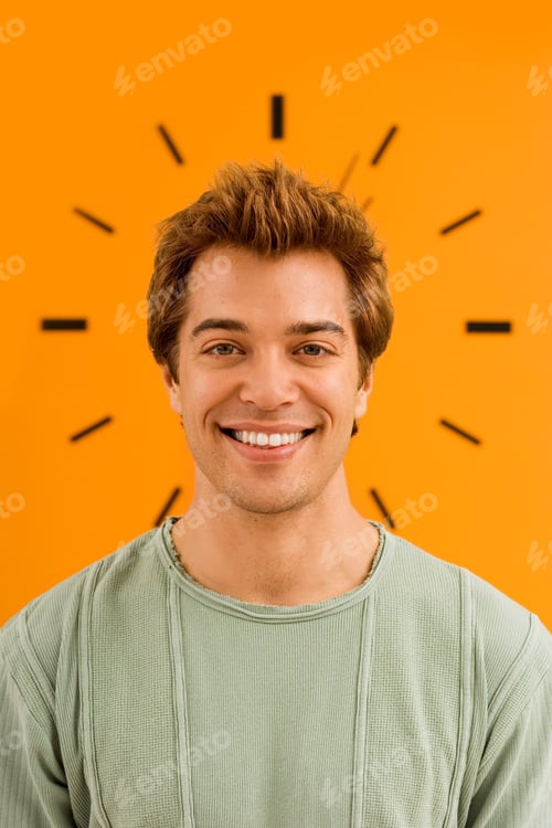 Preview: Office Worker Smiling At Camera With Time Clock On Orange Wall In Casual Clothes