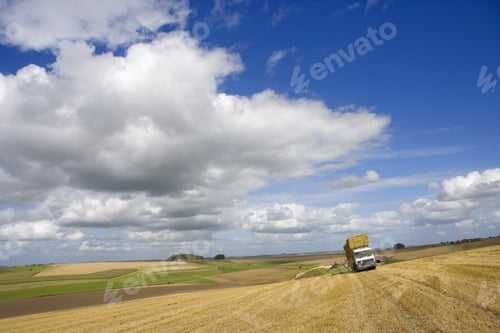 Preview: Clouds In Sunny Blue Sky Over Trailer Loaded With Straw Bales In Harvested Field