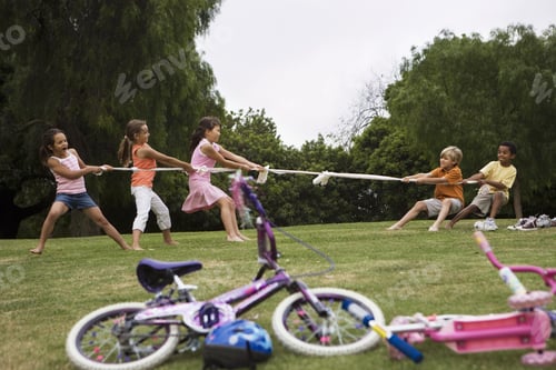 Preview: Group Of Children Playing Tug-Of-War In Park Near Bicycles, Boys Versus Girls, Side View