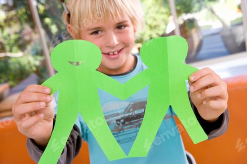 Preview: Portrait Of Boy Cutting Out Chain Of Figures From Paper At Home