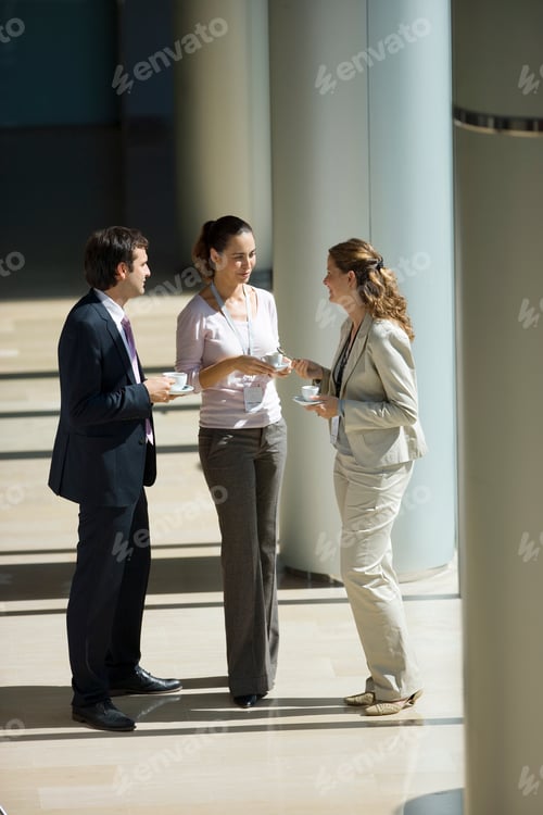 Preview: Businessman And Businesswomen Having Informal Meeting In Office Lobby And Drinking Coffee
