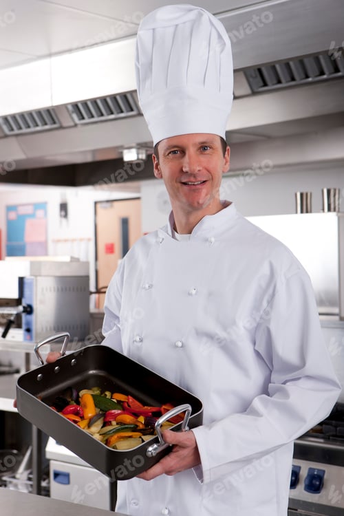 Preview: Chef Holding Pan Of Vegetables In Commercial Kitchen Smiling At Camera