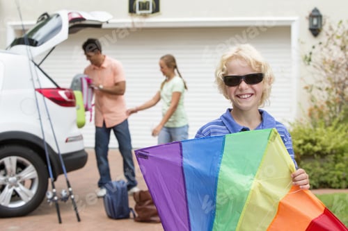 Preview: Portrait Of Smiling Boy Holding Multicolor Kite In Driveway