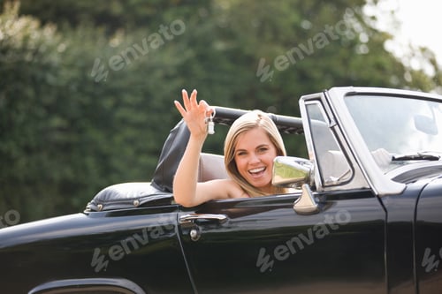 Preview: Young Woman With Keys To Classic Convertible Black Sports Car Smiling At Camera