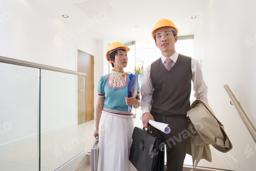Preview: Young Businessman And Woman In Hard Hats In Office, Woman Looking At Man, Low Angle View,
