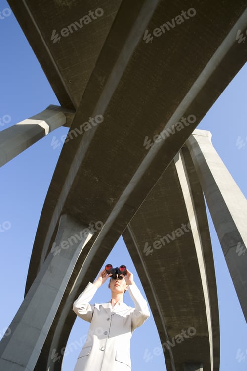 Preview: Businesswoman Using Binoculars Beneath Overpasses, Low Angle View