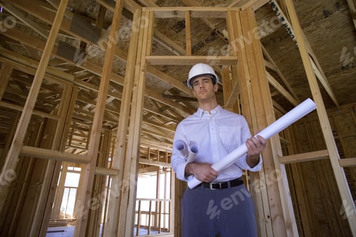 Preview: Young Male Architect With Blueprint In Partially Built House, Smiling, Portrait, Low Angle View