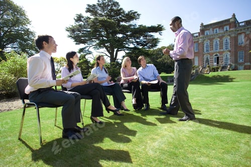 Preview: Businessmen And Women On Training Course Outdoors By Manor House