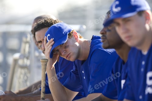Preview: Dejected Baseball Team, In Blue Uniform, Sitting On Bench In Stand During Competitive Baseball