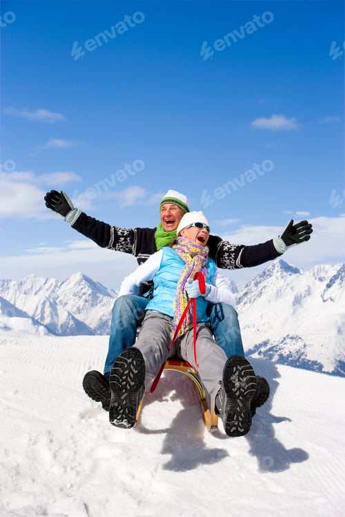 Preview: Laughing Senior Couple On Winter Vacation Riding Sled Down Mountain