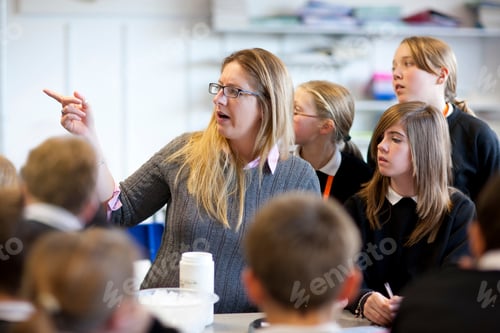 Preview: Female Teacher Helping High School Students In Classroom Lesson