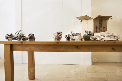 Preview: Crockery Wrapped In Paper Beside Cardboard Box On Dining Room Table
