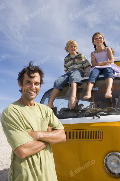 Preview: Man On Beach With Arms Crossed By Son And Daughter (5-9) On Roof Of Camper Van, Portrait, Low Angle