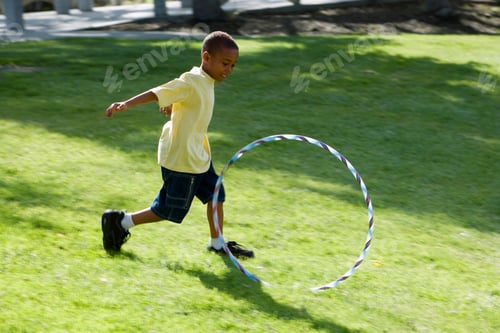 Preview: Action Shot Of Boy Chasing Plastic Hoop On Grass In Summer Park
