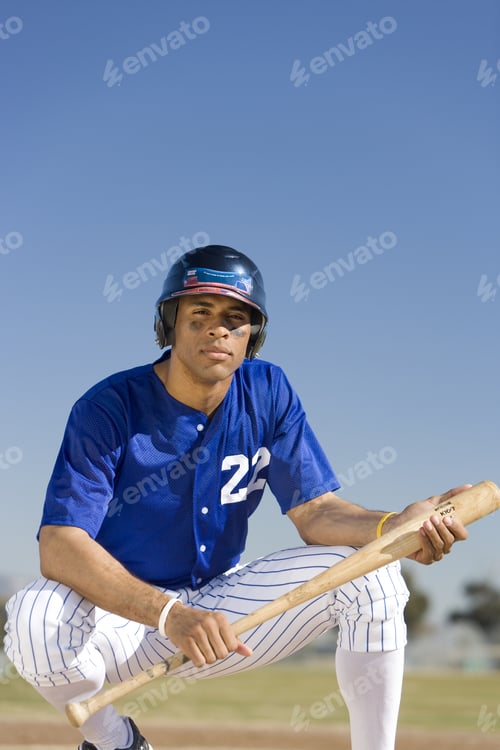 Preview: Baseball Player Wearing Blue Uniform And Cap, Crouching On Pitch, Holding Bat, Front View, Portrait