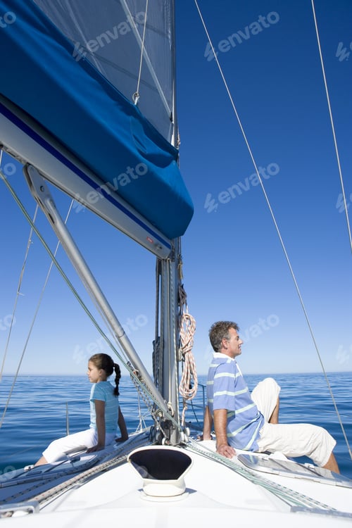 Preview: Father And Daughter (8-10) Sitting Back To Back At Bow Of Sailing Boat, Smiling, Profile