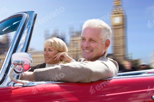Preview: Couple Driving Convertible Car Past Houses Of Parliament In London Uk