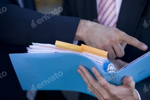Preview: Businessmen Discussing Paperwork In Binder