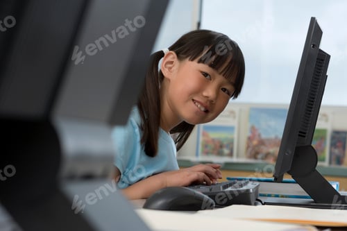 Preview: Female Elementary Student Working On Computers At Desk In It Class At Camera