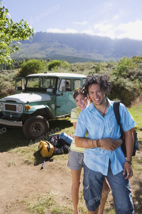 Preview: Young Couple Standing Near Parked Jeep At Start Of Camping Holiday, Woman Embracing Man, Smiling