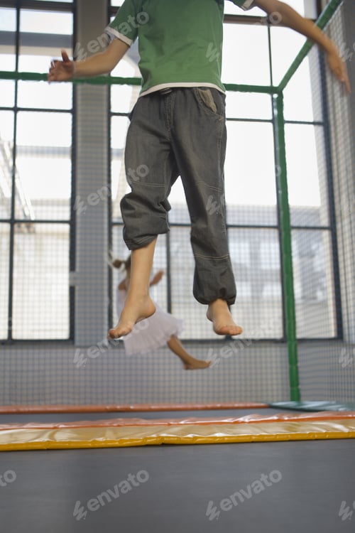Preview: Low Section View Of A Boy With A Girl Jumping On A Trampoline