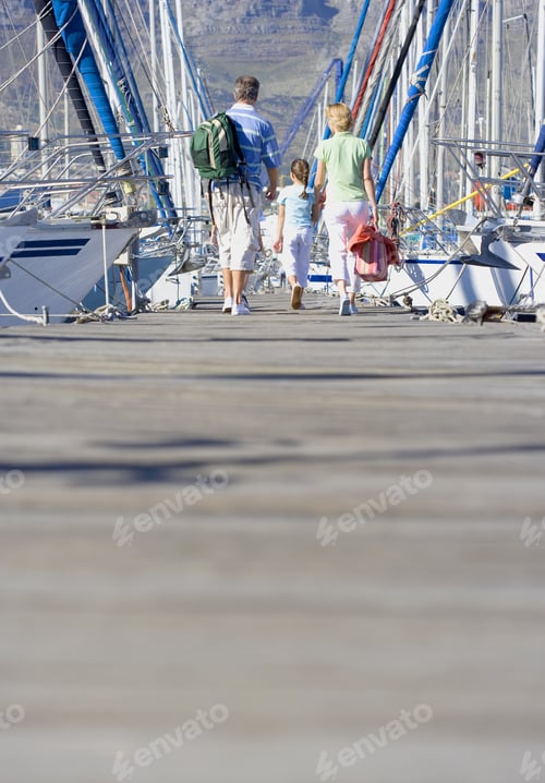 Preview: Family Walking Side By Side In Mid-Distance Along Harbour Jetty, Rear View
