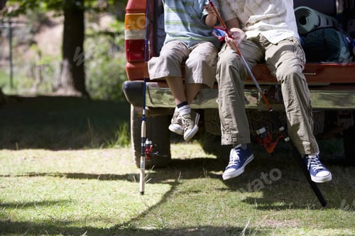 Preview: Father And Son Sitting With Fishing Poles On Edge Of Truck Bed