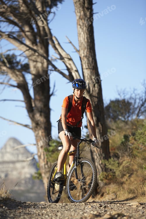 Preview: Female Mountain Biker Cycling Along Tree-Lined Mountain Path, Portrait