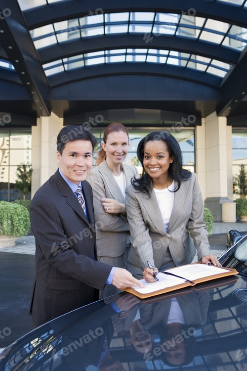 Preview: Businessman And Two Businesswomen Signing Contract Outside Hotel, Leaning On Car, Smiling, Portrait