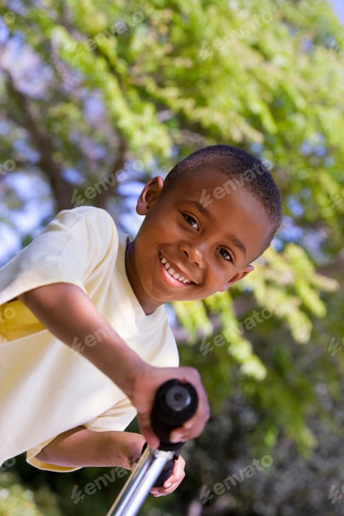 Preview: Portrait Of Boy Having Summer Fun Playing In Park On Scooter Wearing Yellow T-Shirt