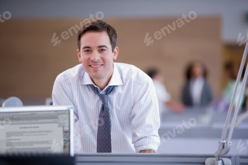 Preview: Businessman Working At Desk In Busy Office Smiling At Camera