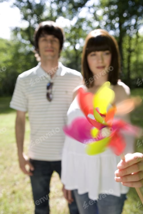 Preview: Young Couple Outdoors, Woman Holding Out Pinwheel, Portrait (Blurred Motion)