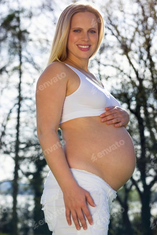 Preview: Portrait Of Smiling Pregnant Woman With Bare Belly In Park