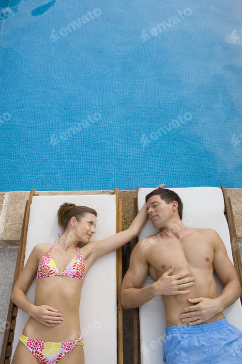 Preview: Couple Laying On Lounge Chairs At Poolside